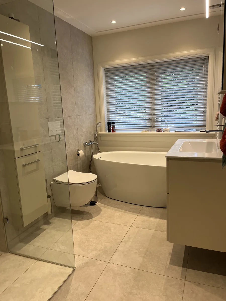Jaren 30 badkamer met compact vrijstaand bad, inloopdouche en wandcloset