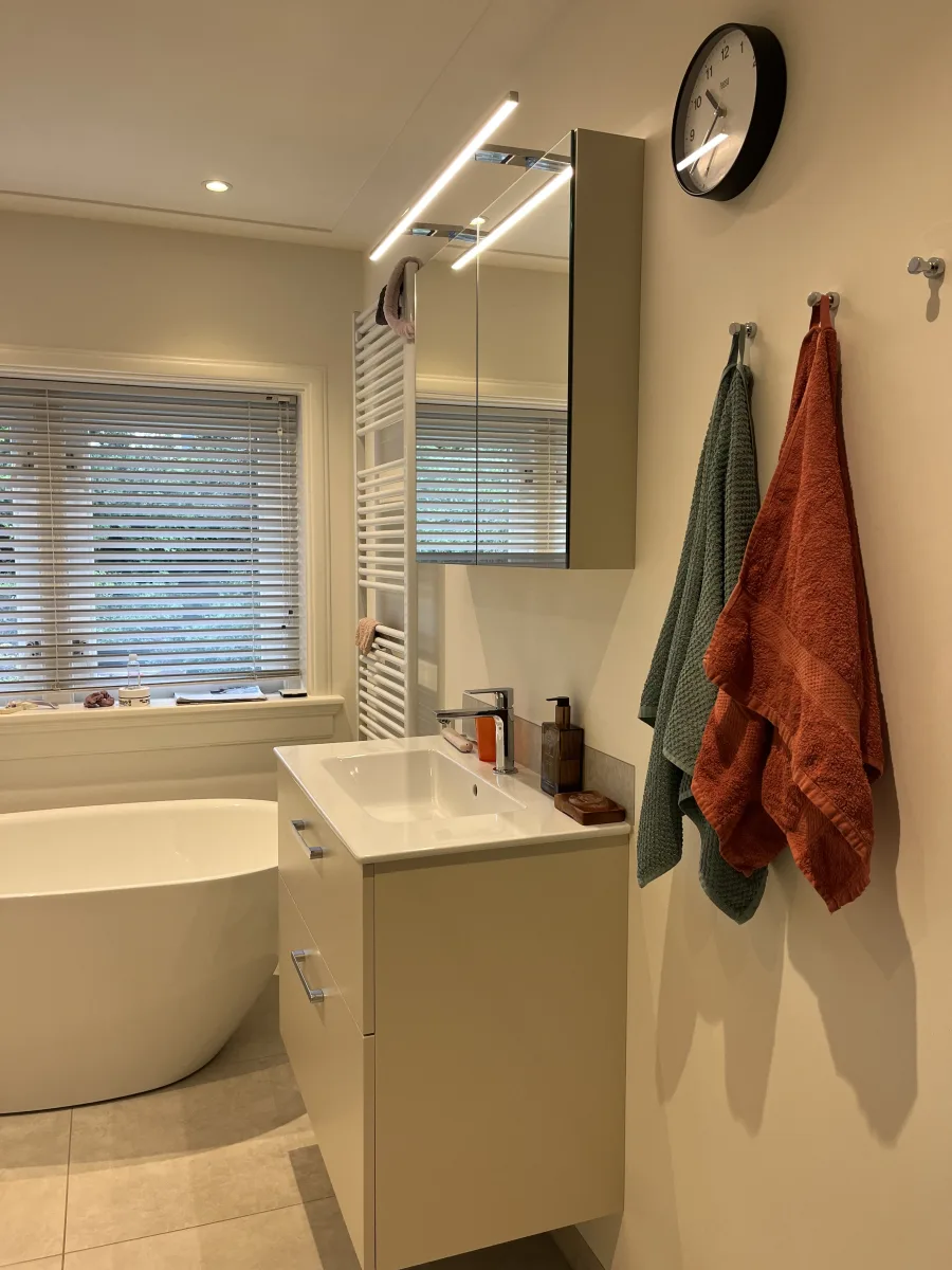 Compact vrijstaand bad van 150 cm onder het raam en badmeubel in pearl beige