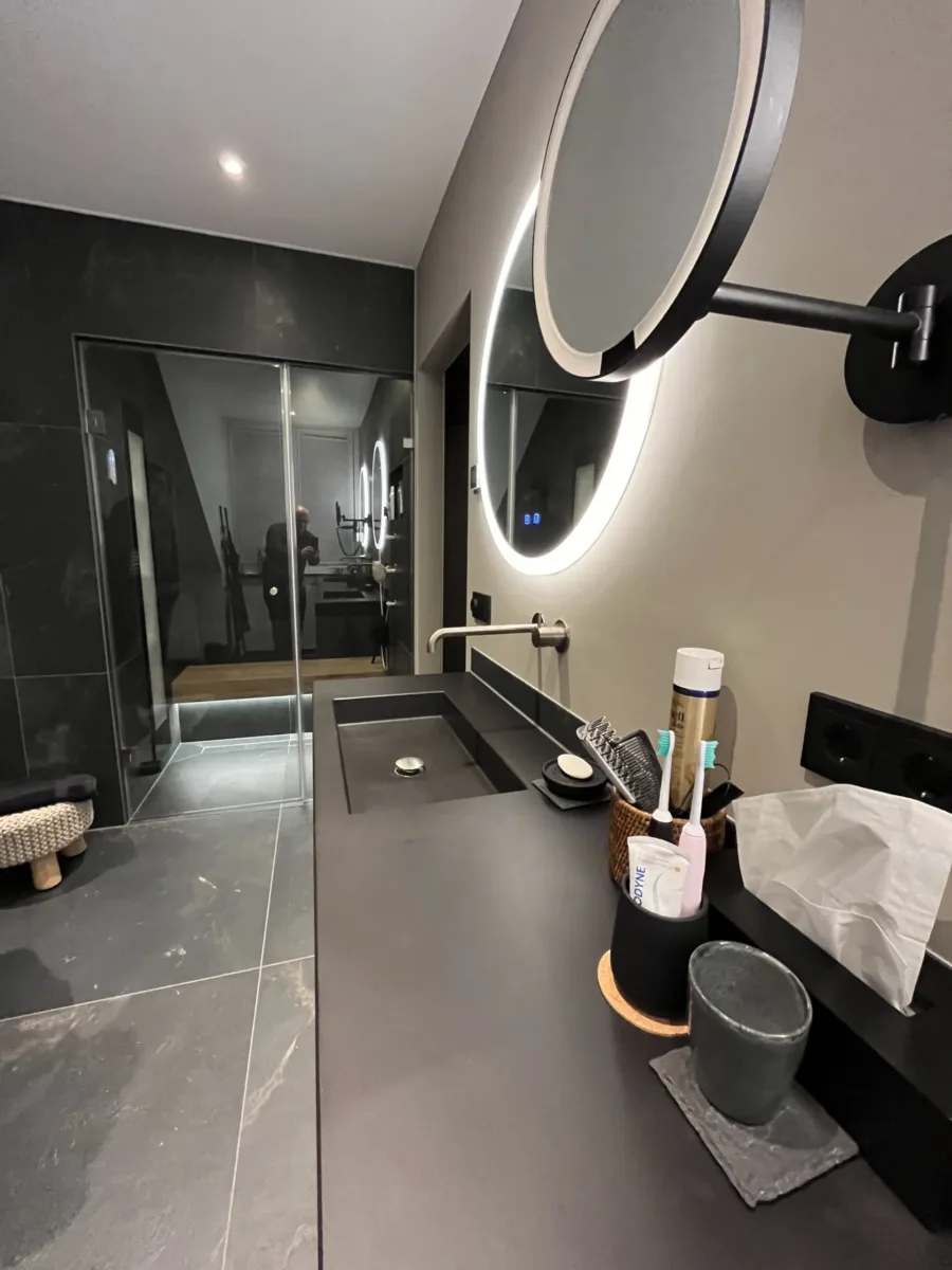 Wellness badkamer met betonnen maatwerk wastafel en ronde verlichte spiegels