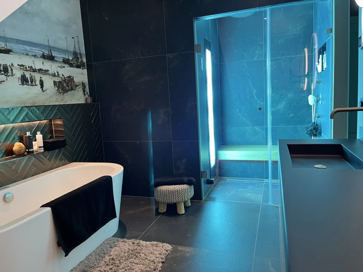 Bouwkundige stoomdouche met blauwe sfeerverlichting naast het bad